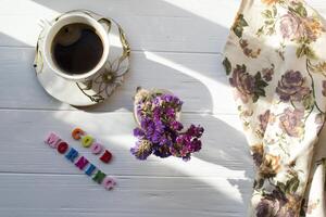 A cup of morning coffee and home decor on a white wooden table. photo