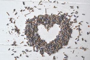 Heart symbol from the lavender flowers on the white wooden table. Lavender flavor. photo