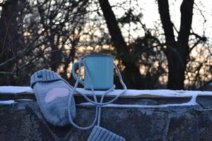 A mug of tea and mittens in the garden. A cup of tea outdoor. photo