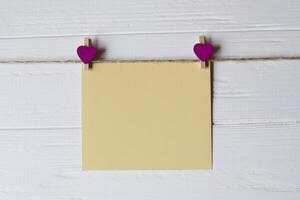 Yellow memo sheet fastened with a decorative pin on a white wooden board. photo