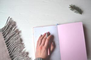 A female hand holds a pen. White table. Stylish background. photo