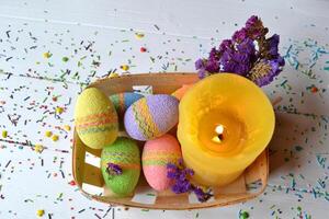 Colorful easter eggs with flowers and yellow candle in the basket. Beautiful easter background. Easter card. Homemade holiday decor. photo