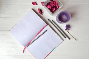 Composition with sketchbook, pencils and decoration elements on the white wooden desk. Inspirational flat lay. Background with place for text. photo