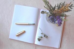 Opened notebook and pen on the pink concrete table. Beautiful business flat lay. photo