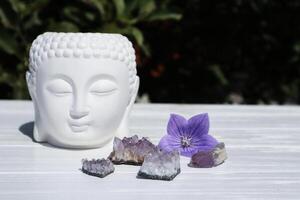 Amethyst stones near statue head of Buddha. Meditation place. photo