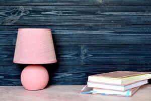 Pink table lamp and books on the desk. Bright background with place for text. photo