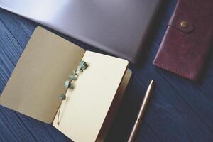 Notebook and objects of decoration on the wooden desk. Inspirational vintage workplace photo