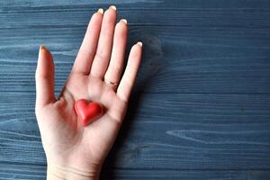 Red candies in a form of heart in woman's hand. Background for greeting card on a Valentine's day. photo