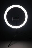 LED ring lamp with smartphone holder in the dark. photo