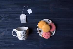 vacío taza, té bolso y platillo con postre en oscuro azul de madera antecedentes. foto