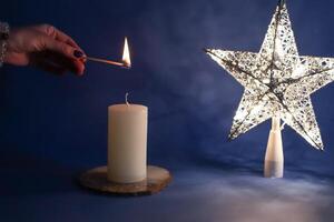 Woman lights candle near light star. photo