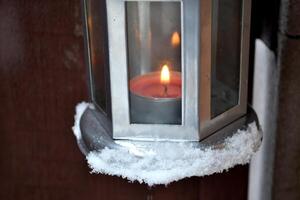 Candle lantern hanging on the door handle outdoor in winter. Cold season. Hygge style. photo