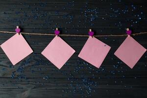 Pink memo sheets fastened with a decorative pin on a dark blue wooden board. photo