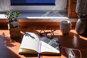 Opened notepad and spectacles on the table. The place of work. photo