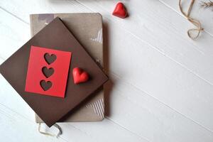 computadora portátil, rojo corazones, cuerda y regalo caja en el blanco de madera escritorio. San Valentín día. antecedentes con sitio para texto. foto