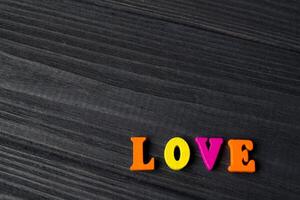 Multicolor letters on a dark blue wooden background. The word love from colorful wooden letters on a table. photo