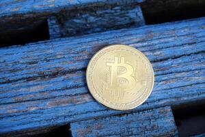 Golden bitcoin on a blue wooden background. A coin of cryptocurrency. photo