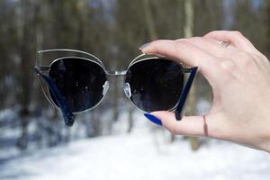 Sunglasses in female hand. Macro shot in a forest. photo