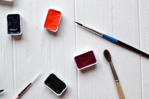 Tools for painting on the white wooden desk. Brushes and paints on the table. Painter's workplace. photo