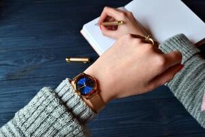 negocio mujer mirando a el reloj en su mano y escritura en el cuaderno. elegante negocio antecedentes. foto