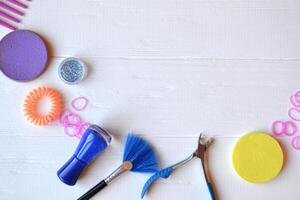 Colorful and bright cosmetics. Beauty care tools. Beauty salon. Girl's paradise. Nail polishes, sequins, pink hair bands and comb on the white wooden desk. Bright still life of beauty instruments. photo