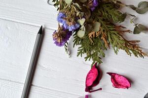 Pencil and flowers on the white wooden background top view. photo