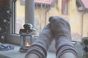 piernas en medias. mujer relajante a hogar cerca el ventana. decoración en el vivo habitación. foto