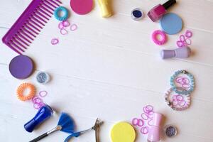 Colorful and bright cosmetics. Beauty care tools. Beauty salon. Girl's paradise. Nail polishes, sequins, pink hair bands and comb on the white wooden desk. Bright still life of beauty instruments. photo