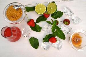 Lime, strawberry, honey and mint on a white table. Ingredients for healthy lemnade. photo