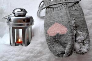 Woolen mittens and candle lantern on the snowdrift. Hygge style. Cold season. photo