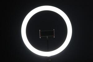 LED ring lamp with smartphone holder in the dark. photo