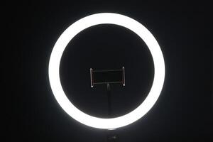 LED ring lamp with smartphone holder in the dark. photo