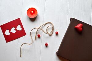 Candle, red hearts, rope and gift box on the white wooden desk. Valentine's Day. Background with place for text. photo