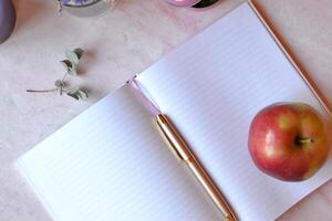 Opened notebook and pen on the pink concrete table. Beautiful business flat lay. photo