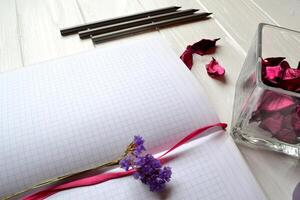 Composition with sketchbook, pencils and decoration elements on the white wooden desk. Inspirational flat lay. Background with place for text. photo