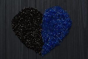 negro y azul pedrería en un formar de corazón en un oscuro azul de madera antecedentes. foto