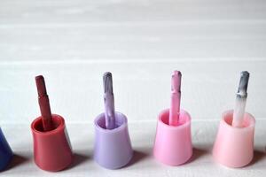 Palette of nail polish on the white wooden background with place for text. Manicure salon. photo