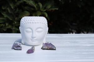 Amethyst stones near statue head of Buddha. Meditation place. photo