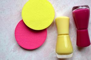 Creative beauty background. Nail polishes and sponges in trendy colors. photo