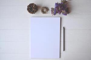 blanco papel y lápiz con decoración en el blanco de madera escritorio, parte superior vista. foto