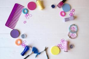 Colorful and bright cosmetics. Beauty care tools. Beauty salon. Girl's paradise. Nail polishes, sequins, pink hair bands and comb on the white wooden desk. Bright still life of beauty instruments. photo