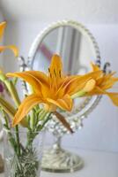 The orange lily near mirror. Flowers and mirror reflection. photo