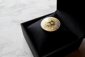 Golden bitcoin in a black box on textured background. Gold coin of cryptocurrency. photo