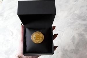 dorado bitcoin en un negro caja en texturizado antecedentes. oro moneda de criptomoneda foto