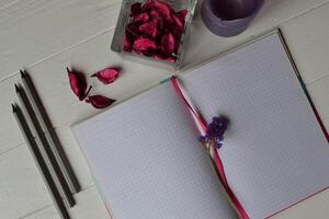 Composition with sketchbook, pencils and decoration elements on the white wooden desk. Inspirational flat lay. Background with place for text. photo