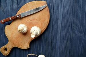 Mushrooms on the dark blue wooden desk. Cooking champignons. photo