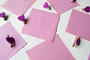 Decorative pins and pink memo sheets on a white wooden background. photo