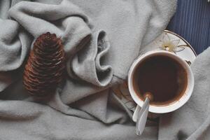 A cup of coffee, cone and knitted sweater in cozy atmosphere on the dark blue wooden background. Atmospheric flat lay in hygge style. photo