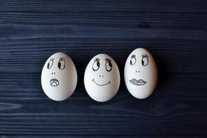 Eggs with a faces in a container box on the wooden table. Creative easter background. Happy easter day. photo