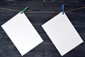 blanco sábana de papel pegado con un pinza de ropa en un de madera pared. foto